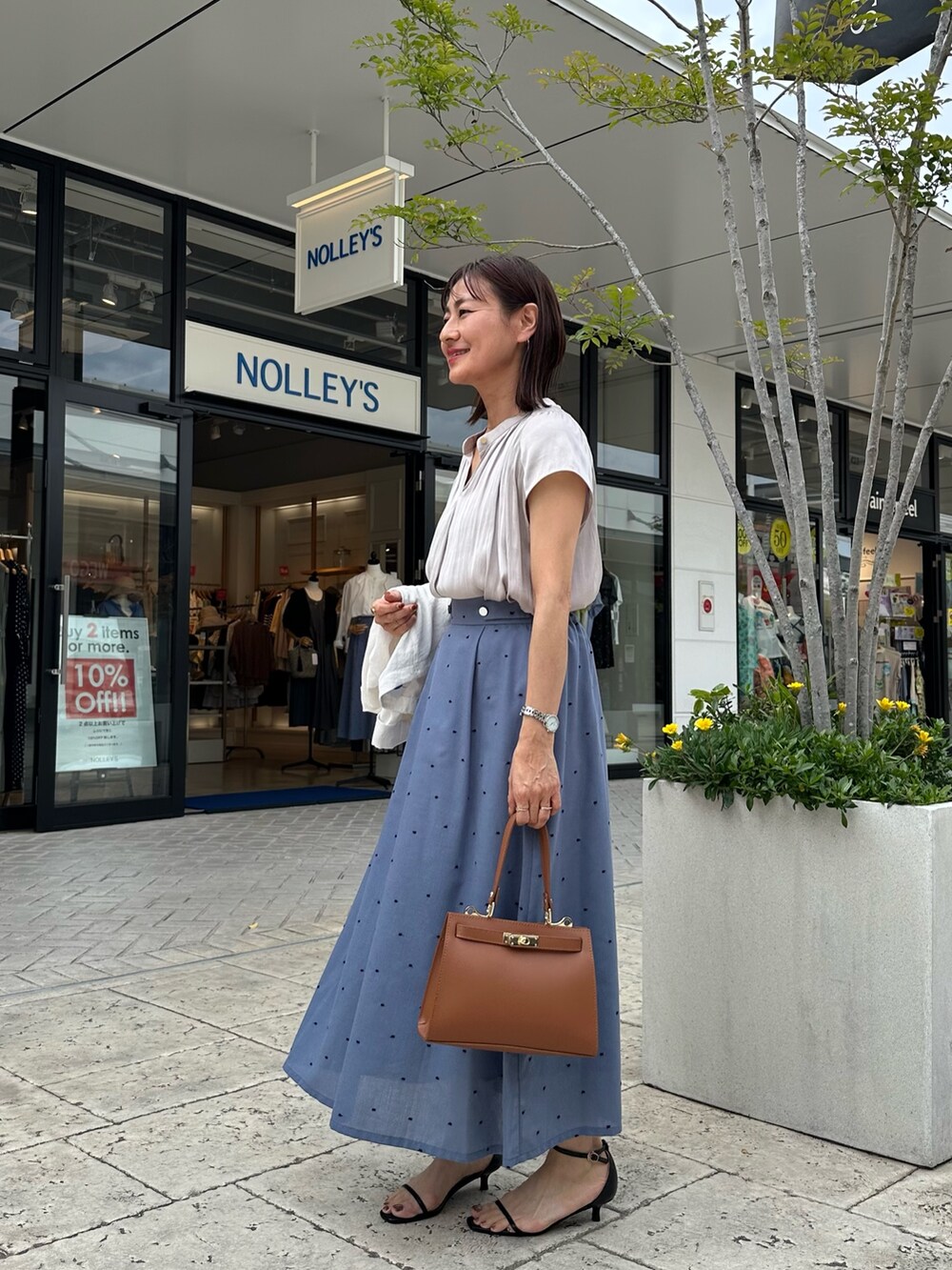 ベージュ系のシャツ/ブラウス、ブルー系のスカート、イエロー系のショルダーバッグを着用したレディースの春コーディネートの3枚目の写真