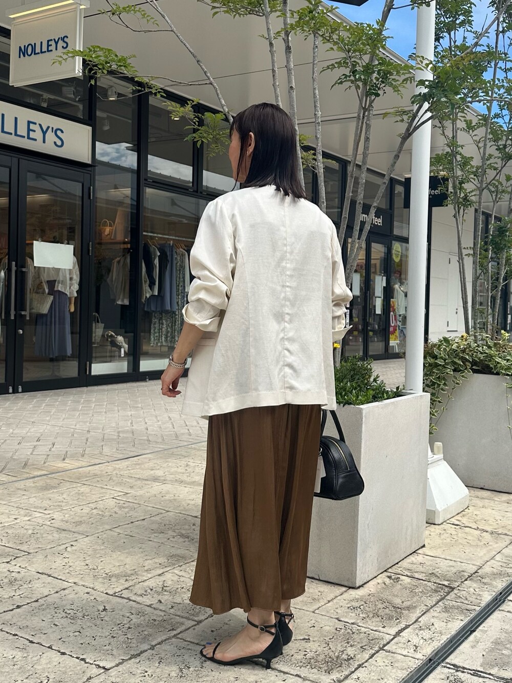 ブラウン系のワンピース、ブラック系のボストンバッグ、ブラック系のサンダルを着用したレディースの夏コーディネートの8枚目の写真