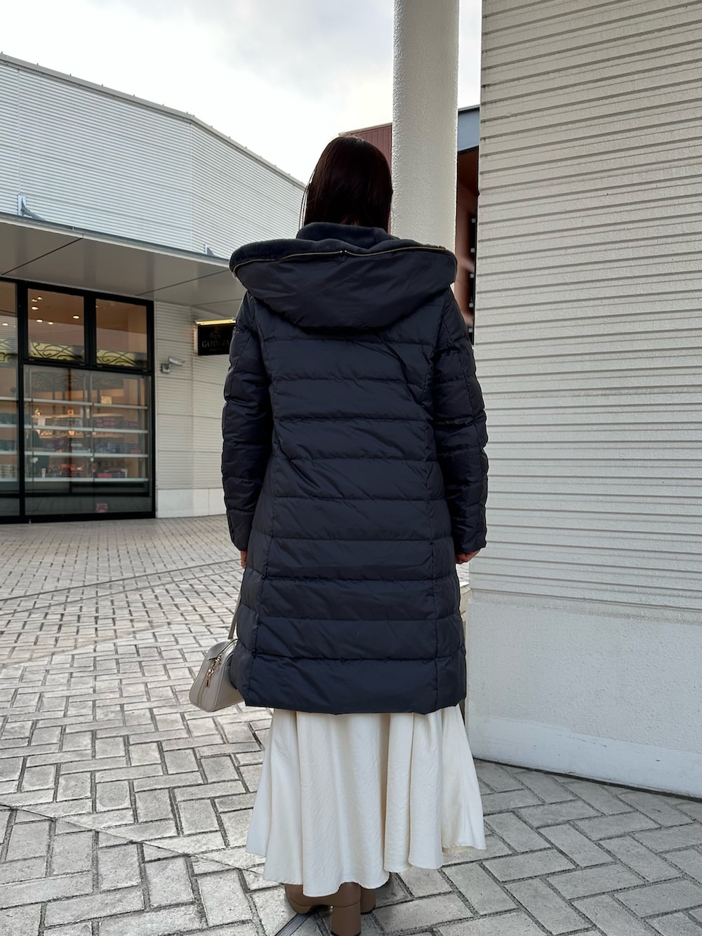 ピンク系のニット/セーター、グレー系のダウンジャケット/コート、ホワイト系のスカートを着用したレディースの冬コーディネートの3枚目の写真