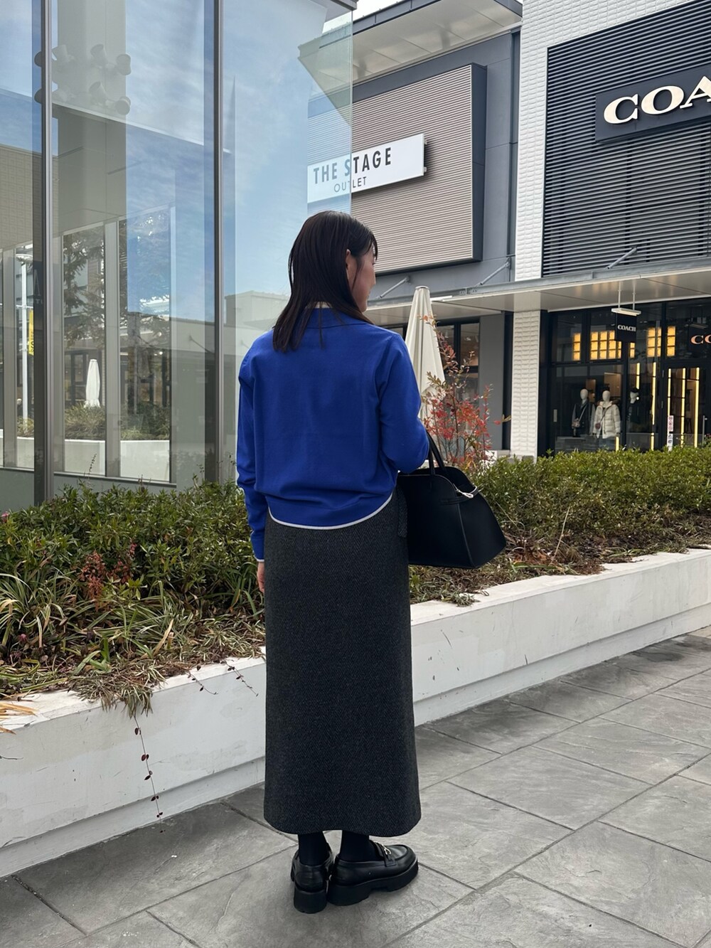 ブルー系のカーディガン/ボレロ、グレー系のスカート、ブラック系のトートバッグを着用したレディースの冬コーディネートの3枚目の写真