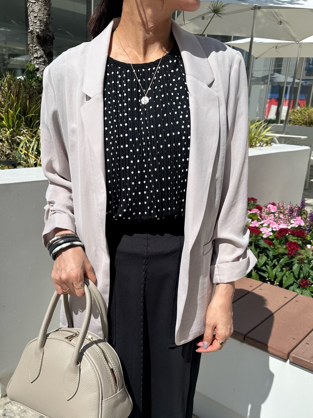 ベージュ系のテーラードジャケット、ブラック系のシャツ/ブラウス、ベージュ系のボストンバッグを着用したレディースの夏コーディネートの4枚目の写真