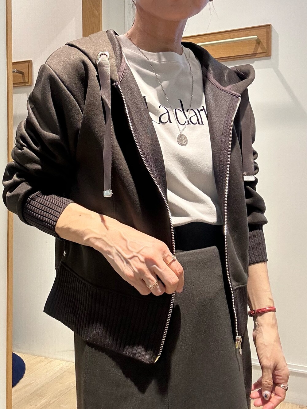 ブラウン系のパーカー、ブラウン系のスカート、ブラック系のショルダーバッグを着用したレディースの秋コーディネートの5枚目の写真