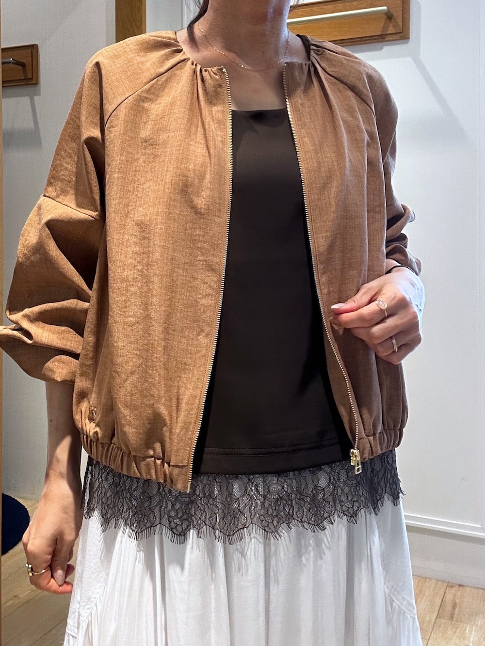 イエロー系のブルゾン、ブラウン系のTシャツ/カットソー、ホワイト系のスカートを着用したレディースの春コーディネートの4枚目の写真