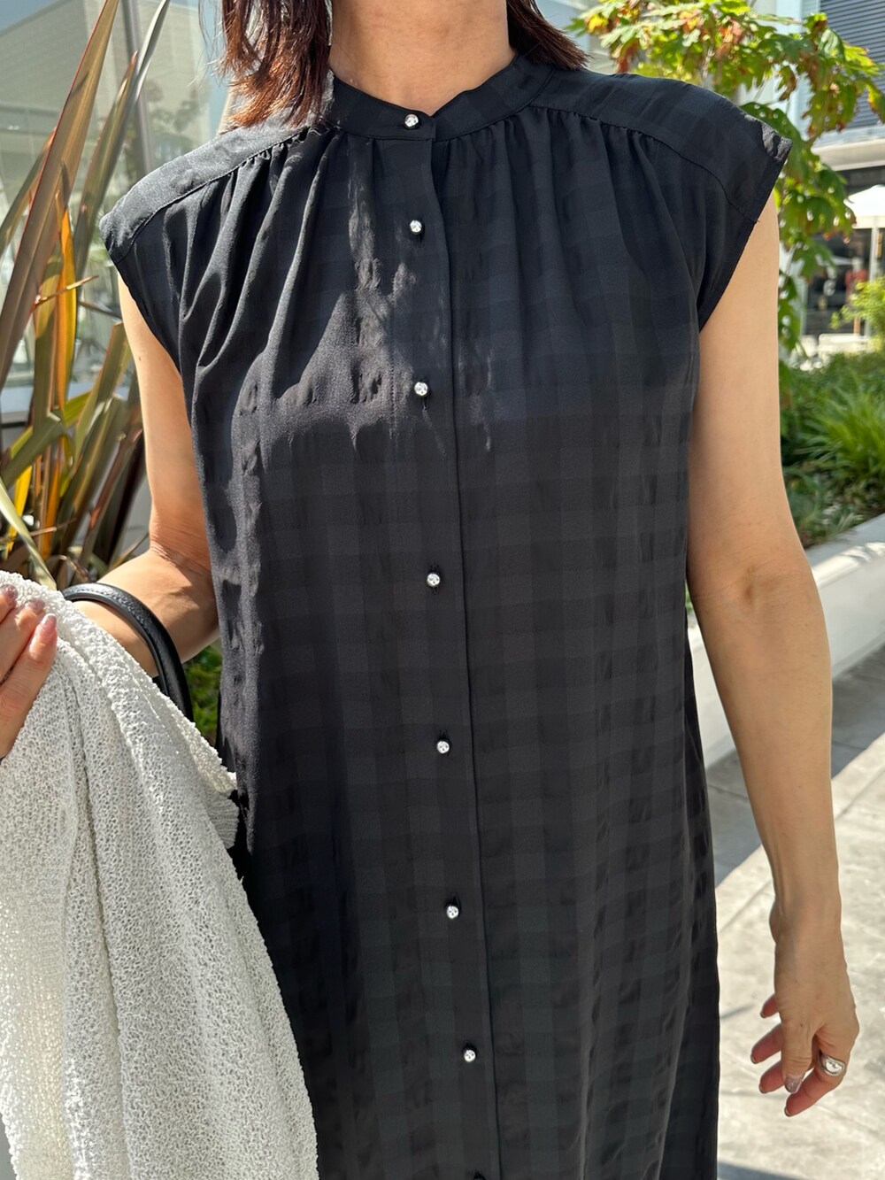 ブラック系のワンピース、ブラック系のサンダル、ホワイト系のカーディガン/ボレロを着用したレディースの夏コーディネートの6枚目の写真