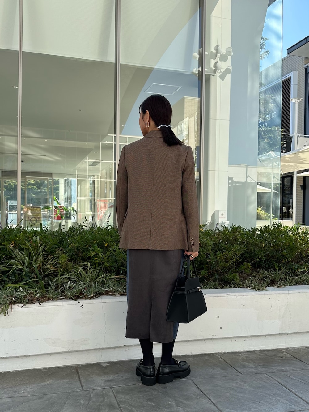 ブラウン系のテーラードジャケット、グレー系のワンピース、ブラック系のトートバッグを着用したレディースの秋コーディネートの2枚目の写真