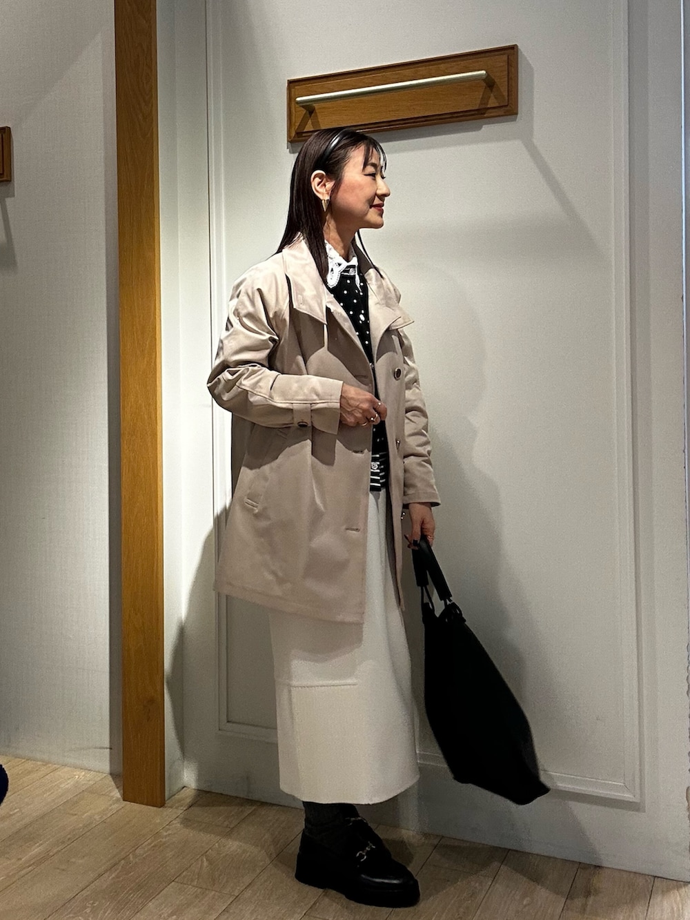 ベージュ系のその他アウター、ブラック系のニット/セーター、ホワイト系のスカートを着用したレディースの冬コーディネートの5枚目の写真