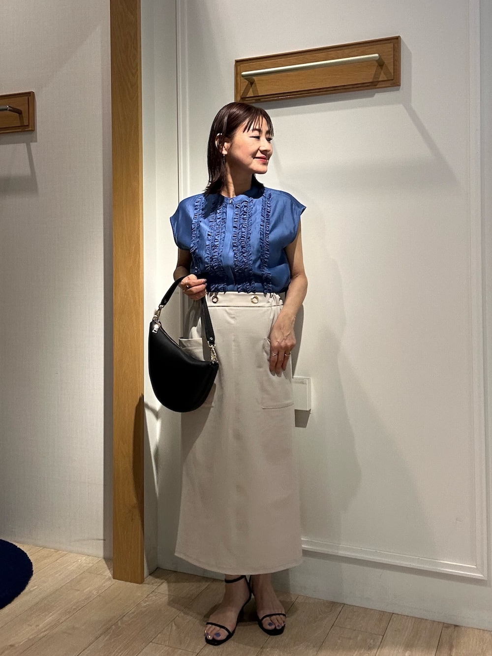 ベージュ系のスカート、ブラック系のショルダーバッグ、ブラック系のサンダルを着用したレディースの夏コーディネートの10枚目の写真