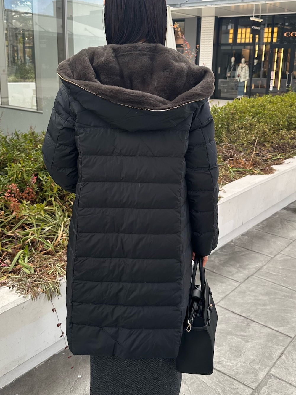 ブラック系のダウンジャケット/コート、グレー系のスカート、ブラック系のトートバッグを着用したレディースの冬コーディネートの10枚目の写真