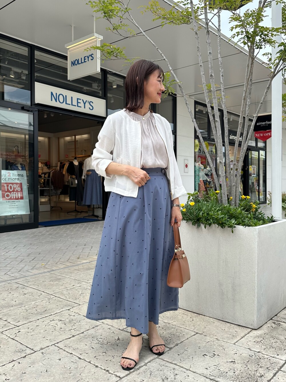 ベージュ系のシャツ/ブラウス、ブルー系のスカート、イエロー系のショルダーバッグを着用したレディースの春コーディネートの10枚目の写真