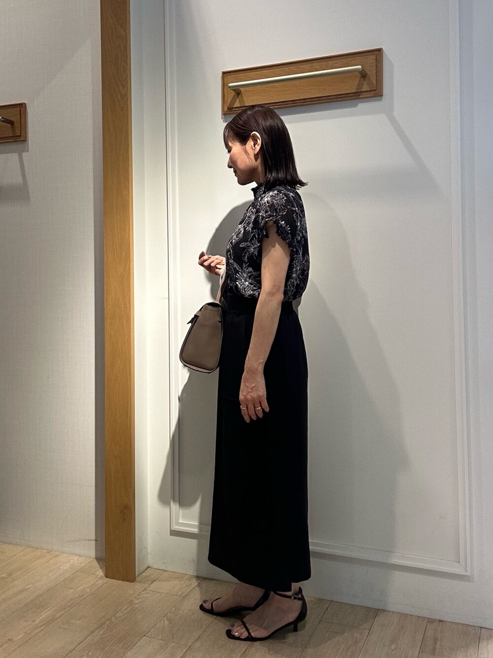 ブラック系のシャツ/ブラウス、ブラック系のスカート、ベージュ系のノーカラージャケットを着用したレディースの夏コーディネートの2枚目の写真