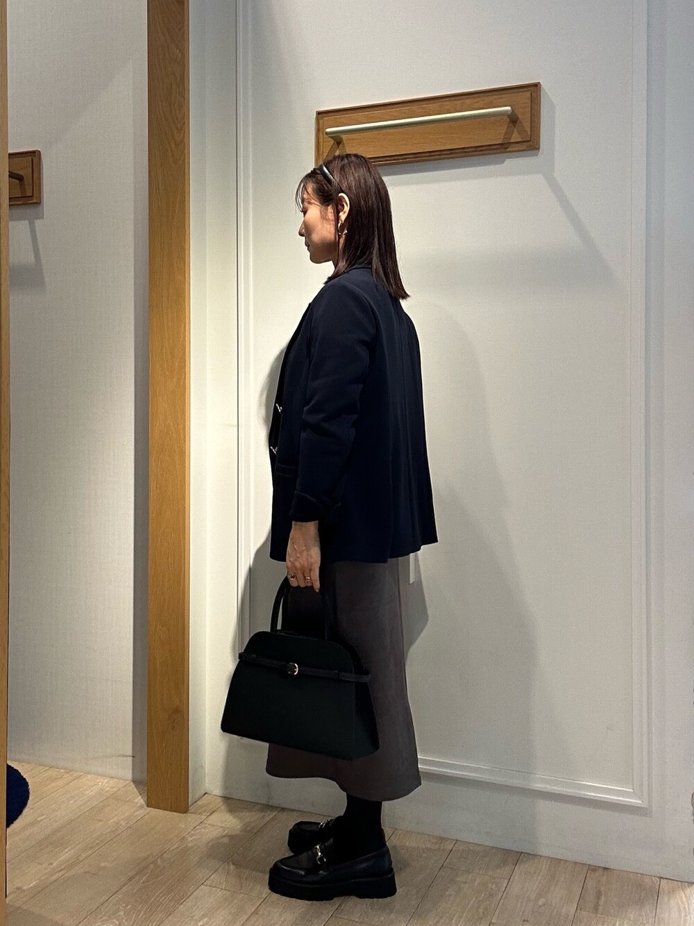 ホワイト系のニット/セーター、ブルー系のテーラードジャケット、グレー系のスカートを着用したレディースの秋コーディネートの2枚目の写真