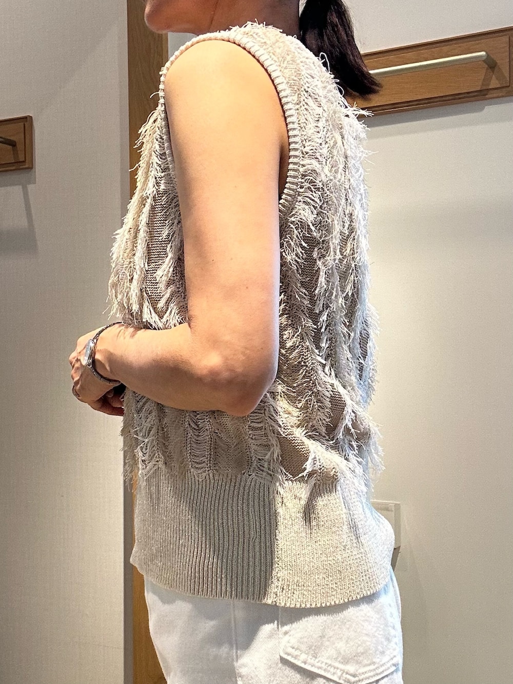 ベージュ系のニット/セーター、ホワイト系のデニムパンツ、ゴールド系のヘアゴムを着用したレディースの夏コーディネートの9枚目の写真