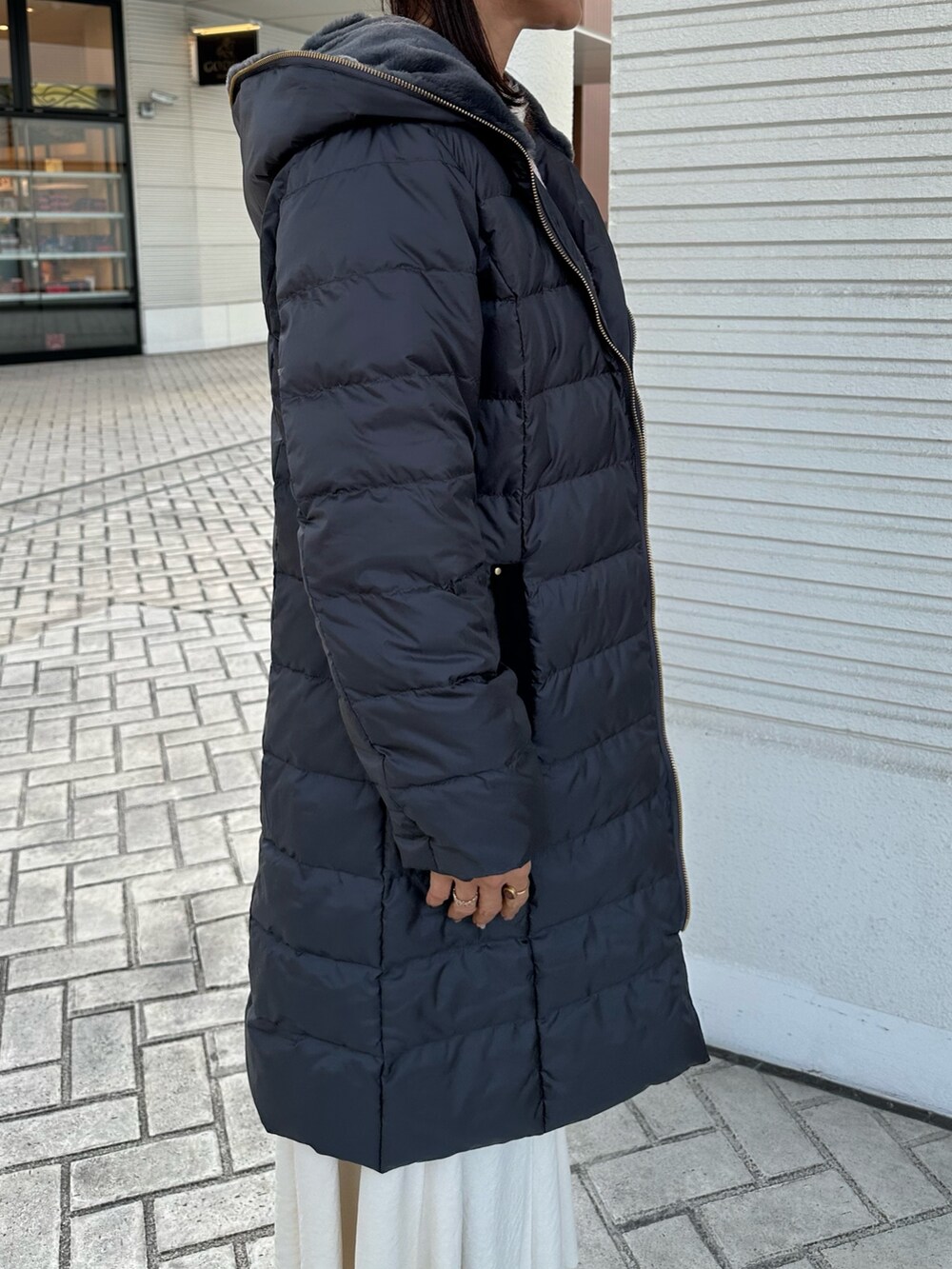 ピンク系のニット/セーター、グレー系のダウンジャケット/コート、ホワイト系のスカートを着用したレディースの冬コーディネートの5枚目の写真