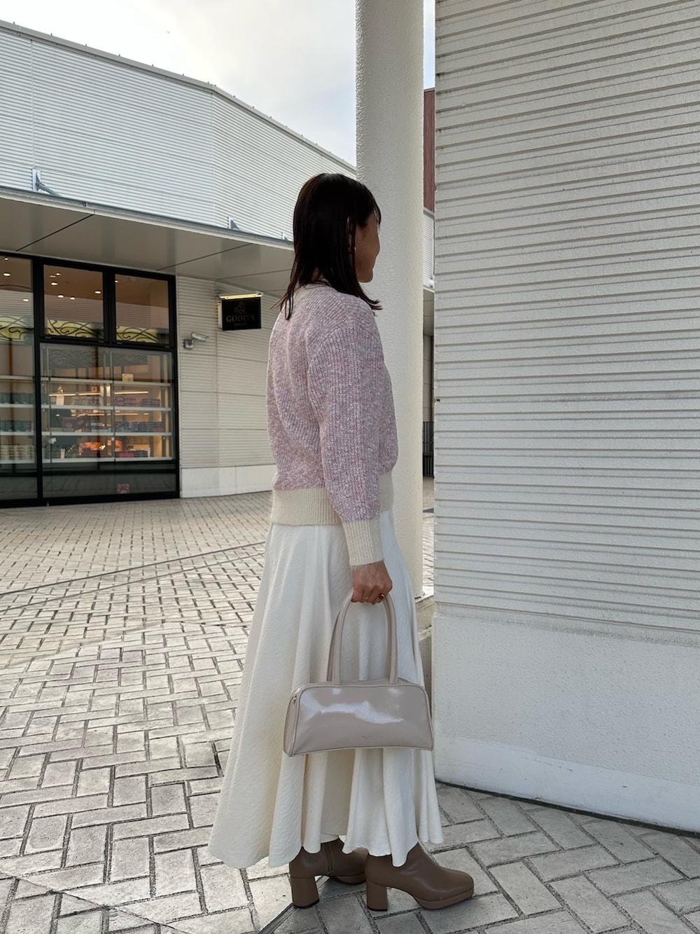 ピンク系のニット/セーター、ホワイト系のスカート、ホワイト系のボストンバッグを着用したレディースの冬コーディネートの4枚目の写真