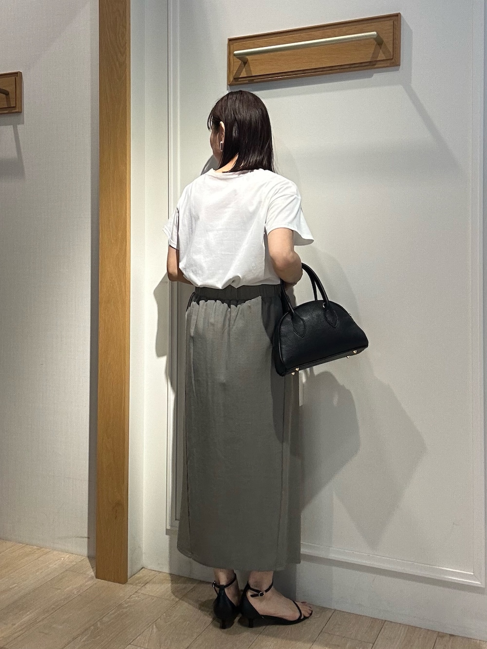 グリーン系のスカート、ホワイト系のTシャツ/カットソー、ブラック系のボストンバッグを着用したレディースの夏コーディネートの2枚目の写真