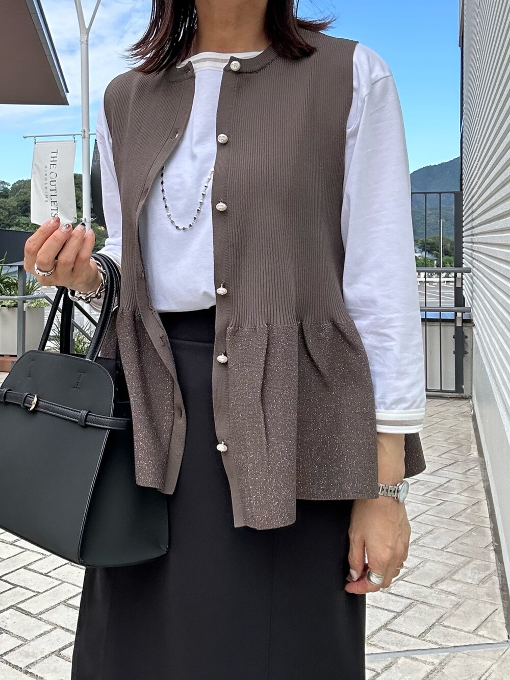 ホワイト系のTシャツ/カットソー、ブラック系のスカート、ブラウン系のニット/セーターを着用したレディースの秋コーディネートの6枚目の写真