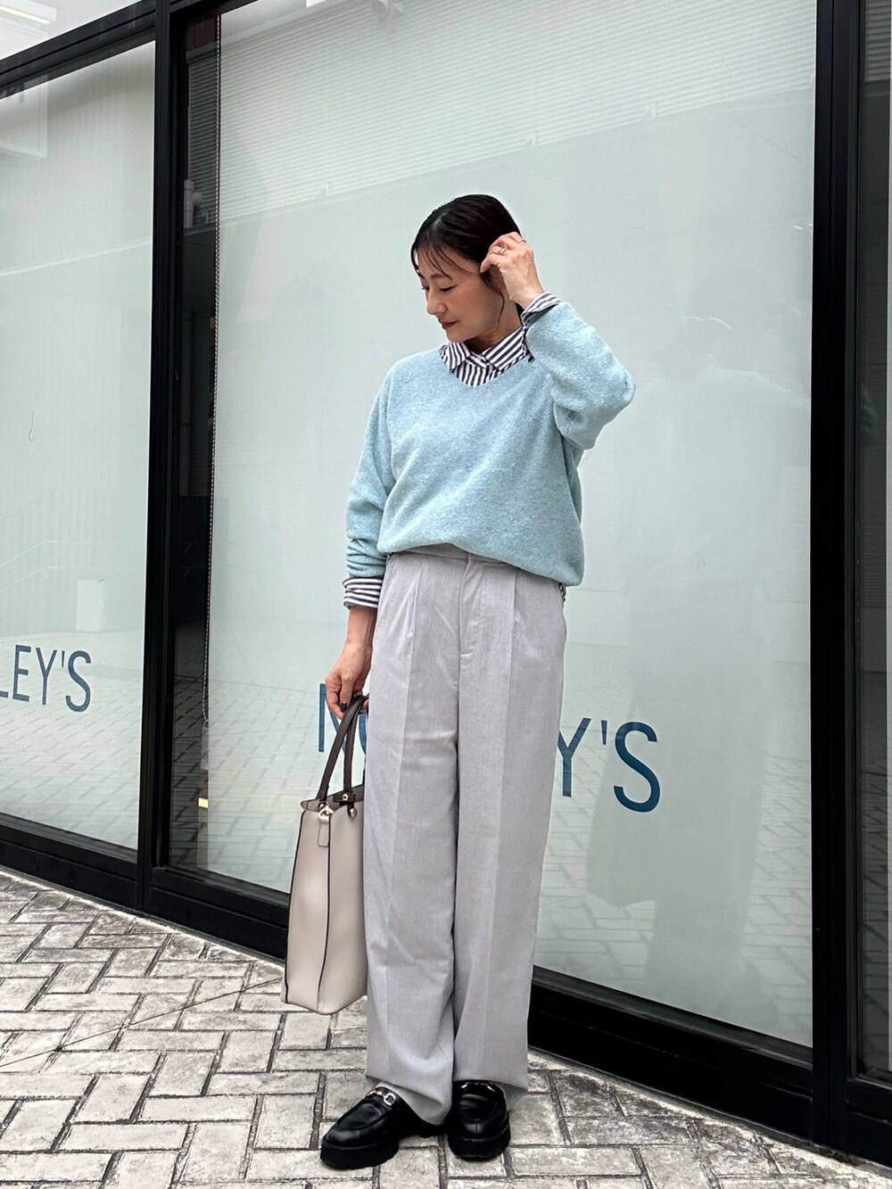 ブルー系のニット/セーター、グレー系のその他パンツ、ブラック系のシャツ/ブラウスを着用したレディースの秋コーディネートの4枚目の写真