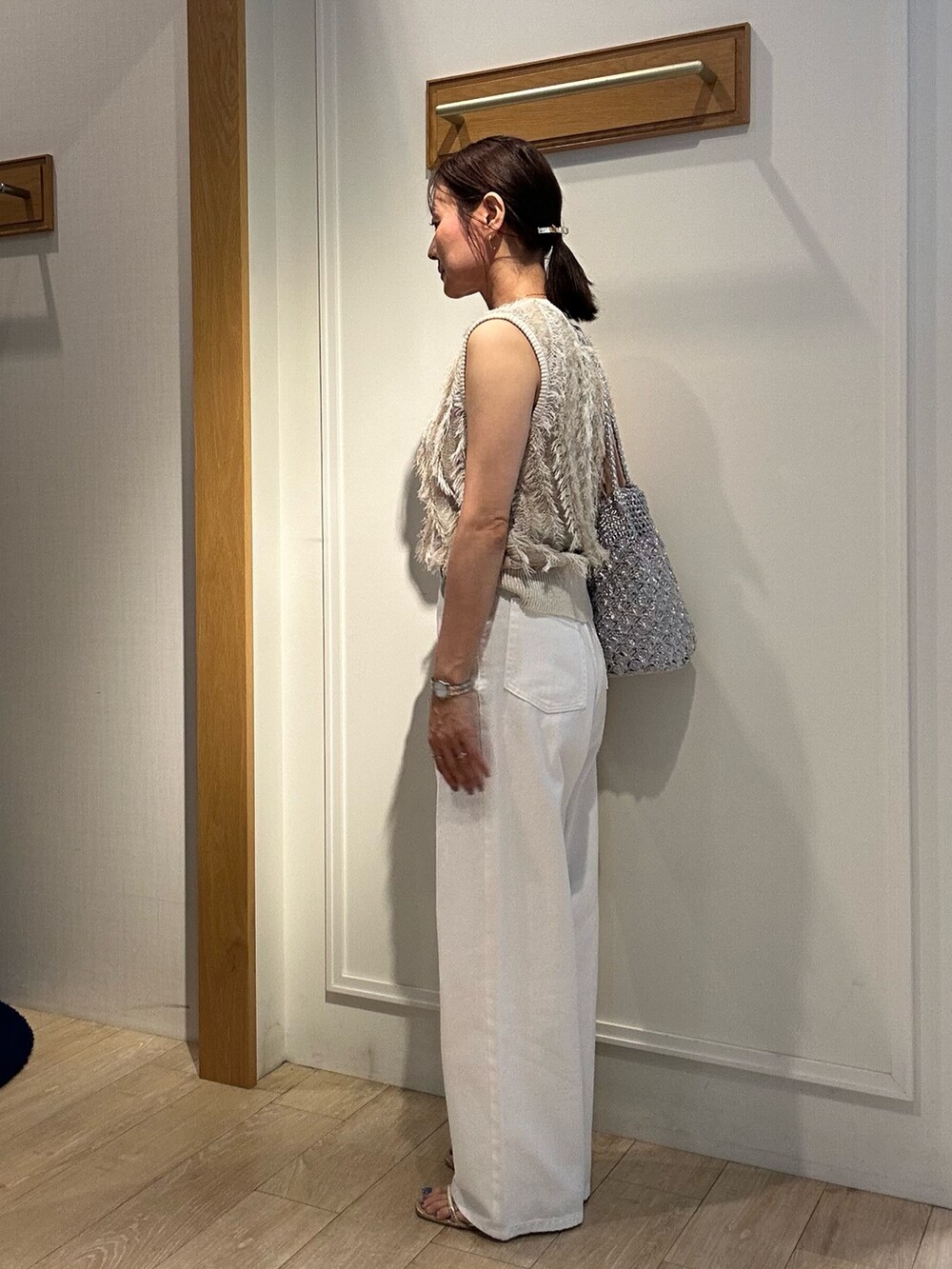 ベージュ系のニット/セーター、ホワイト系のデニムパンツ、ゴールド系のヘアゴムを着用したレディースの夏コーディネートの2枚目の写真