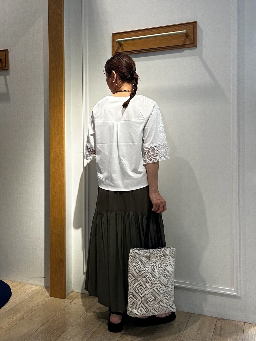 ホワイト系のTシャツ/カットソー、ブラック系のトートバッグ、グリーン系のスカートを着用したレディースの夏コーディネートの3枚目の写真