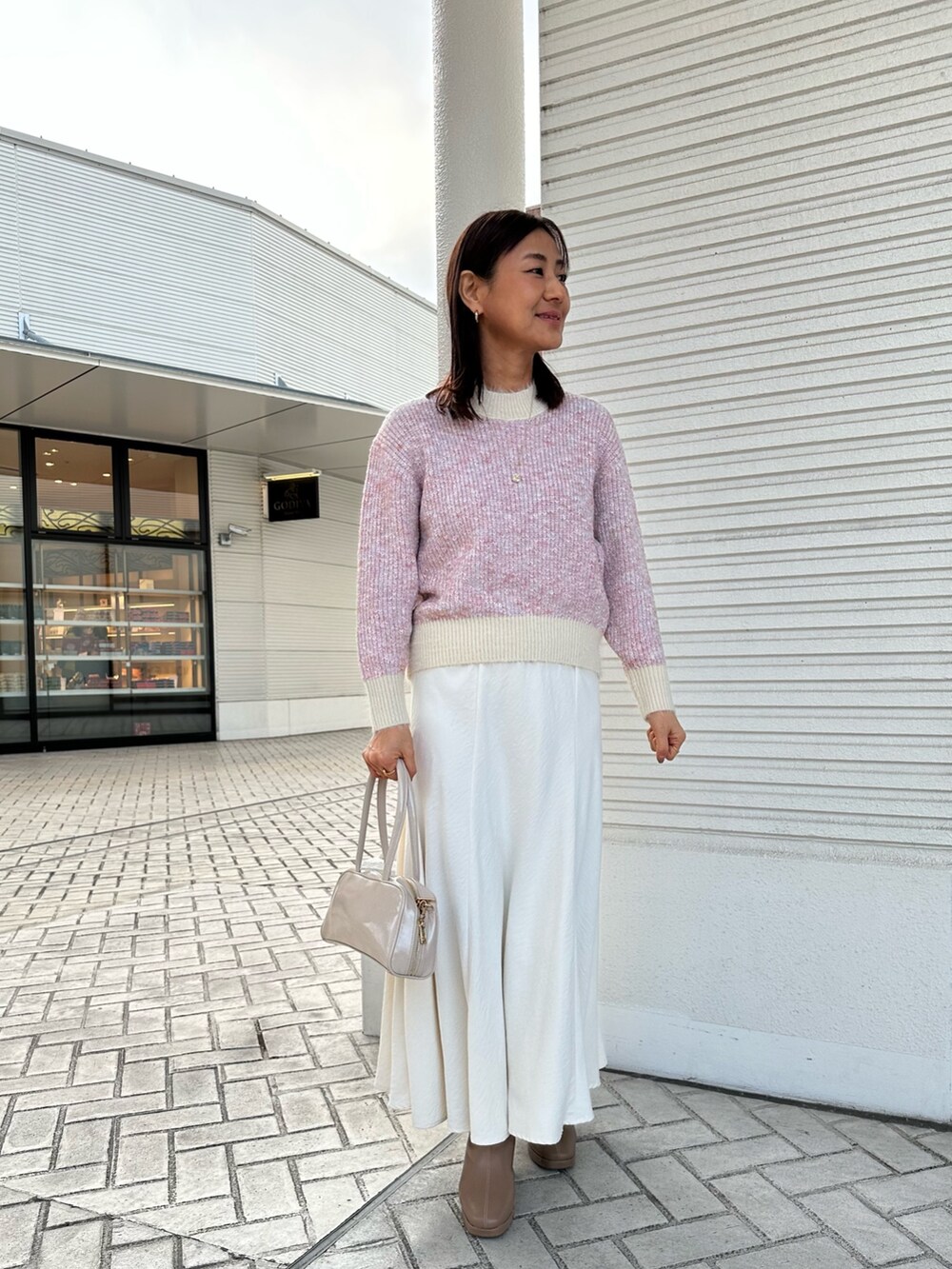 ピンク系のニット/セーター、グレー系のダウンジャケット/コート、ホワイト系のスカートを着用したレディースの冬コーディネートの8枚目の写真