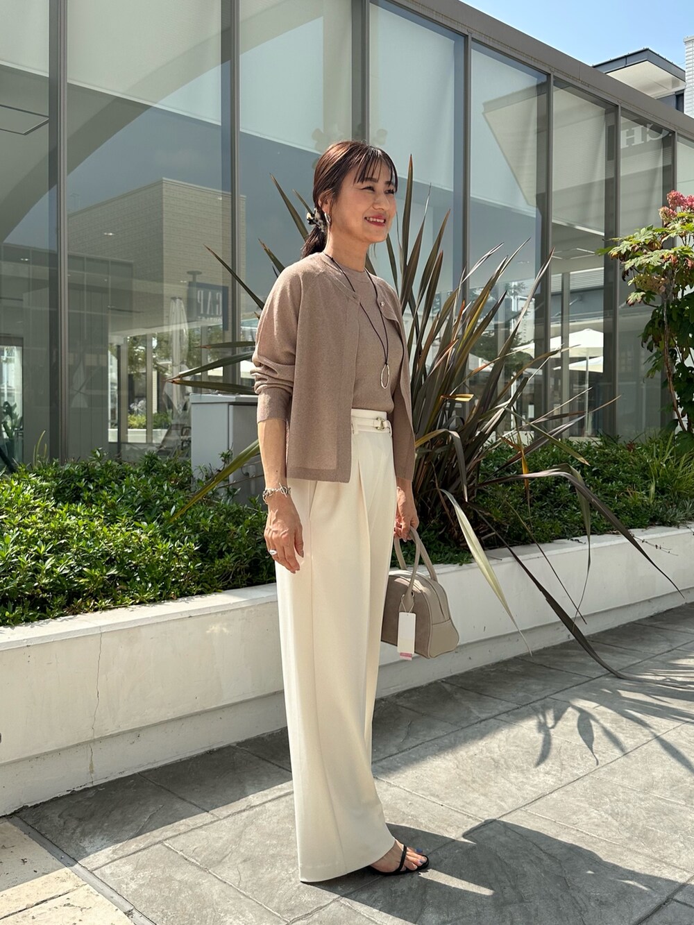 ブラウン系のニット/セーター、ホワイト系のその他パンツ、ベージュ系のボストンバッグを着用したレディースの夏コーディネートの5枚目の写真