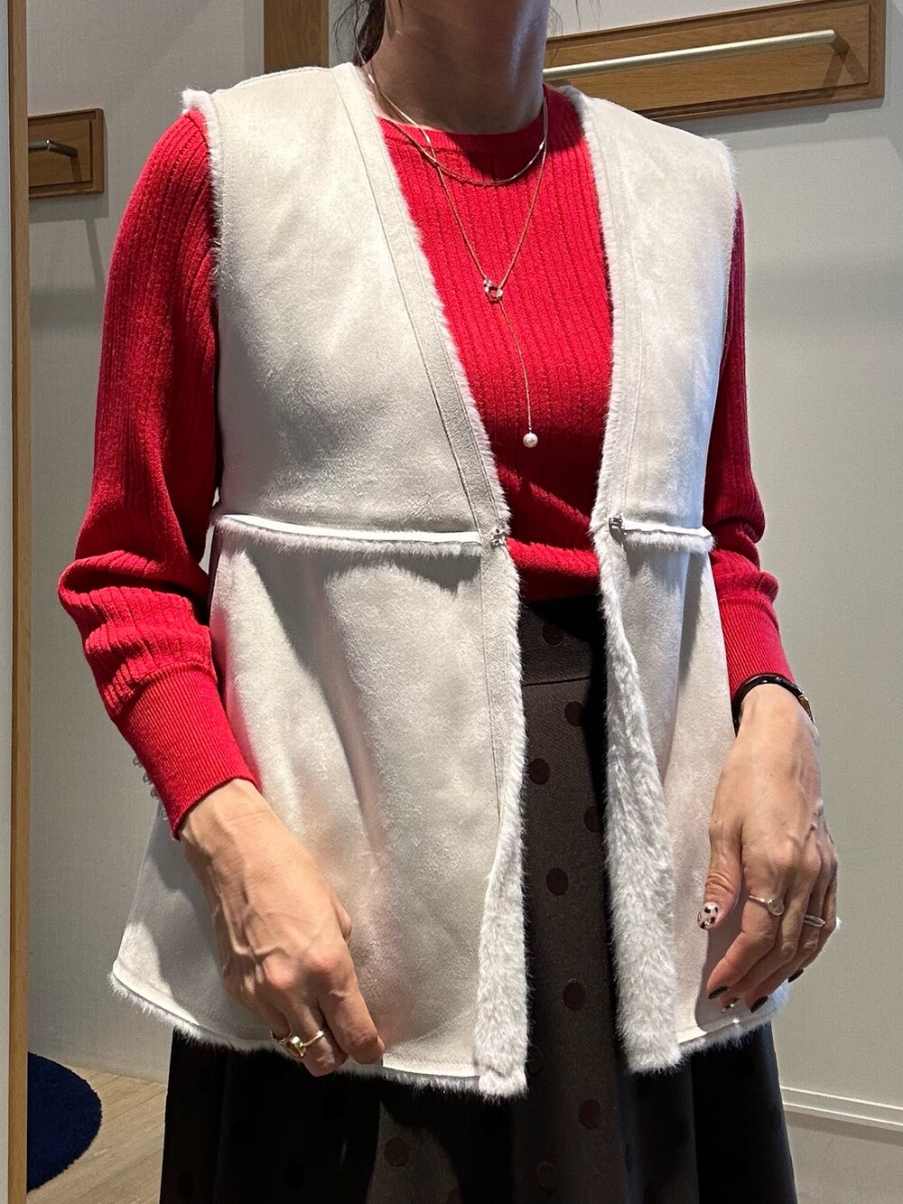 レッド系のニット/セーター、ブラウン系のスカート、ブラック系のトートバッグを着用したレディースの秋コーディネートの8枚目の写真