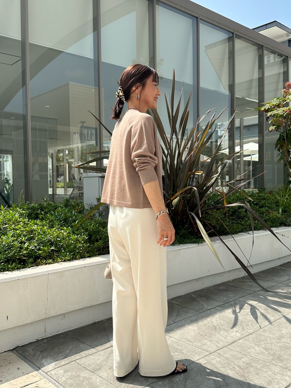 ブラウン系のニット/セーター、ホワイト系のその他パンツ、ベージュ系のボストンバッグを着用したレディースの夏コーディネートの4枚目の写真