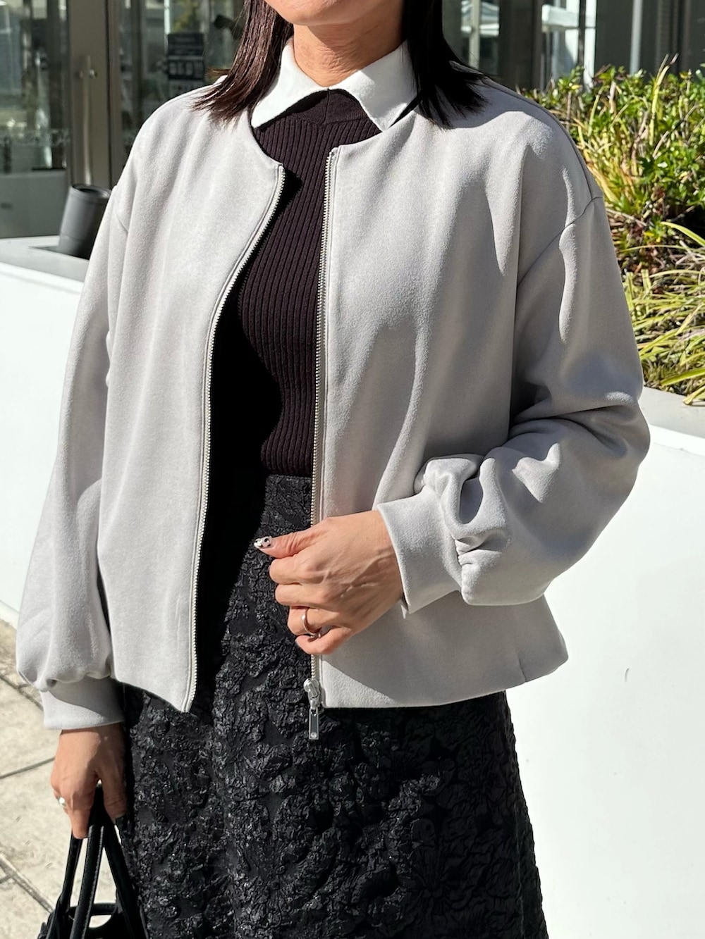 グレー系のブルゾン、ブラック系のニット/セーター、グレー系のスカートを着用したレディースの秋コーディネートの6枚目の写真