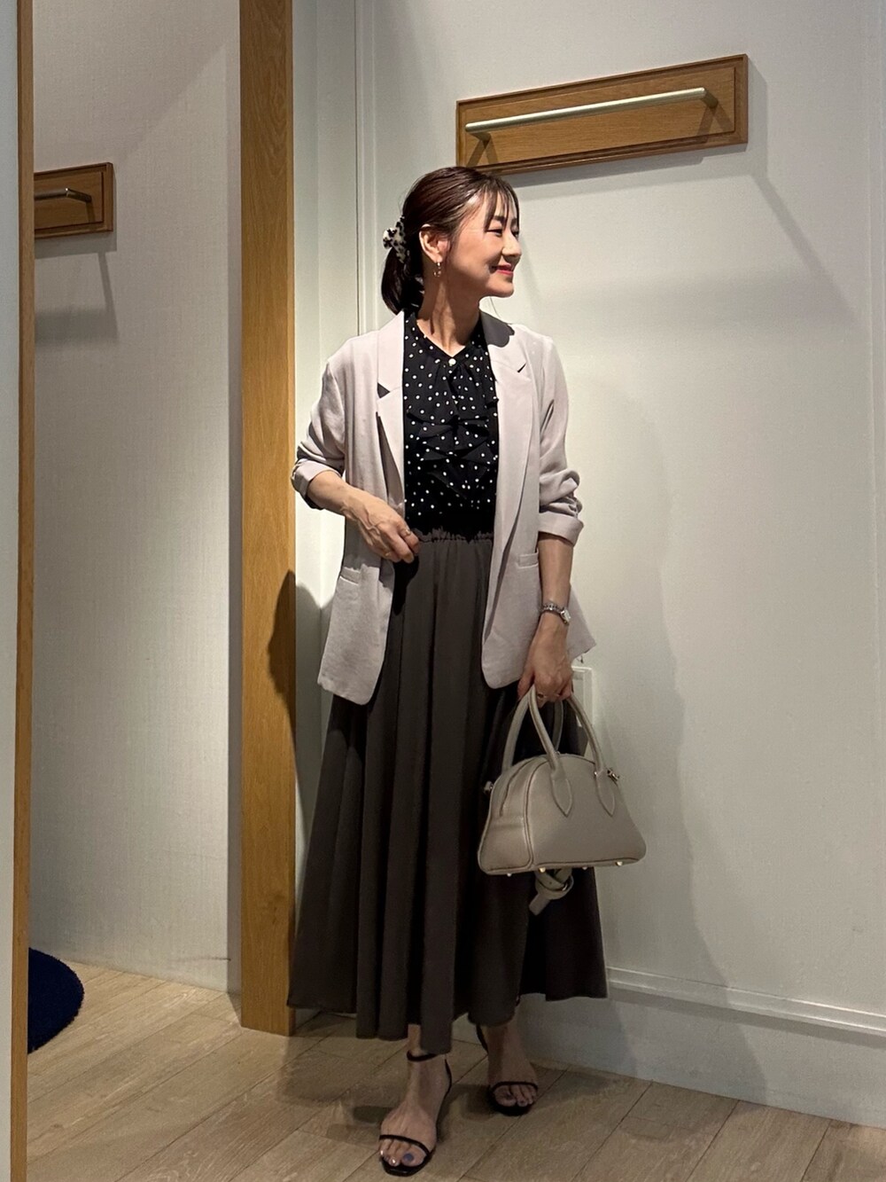 ベージュ系のテーラードジャケット、ベージュ系のボストンバッグ、ブラック系のサンダルを着用したレディースの夏コーディネートの5枚目の写真