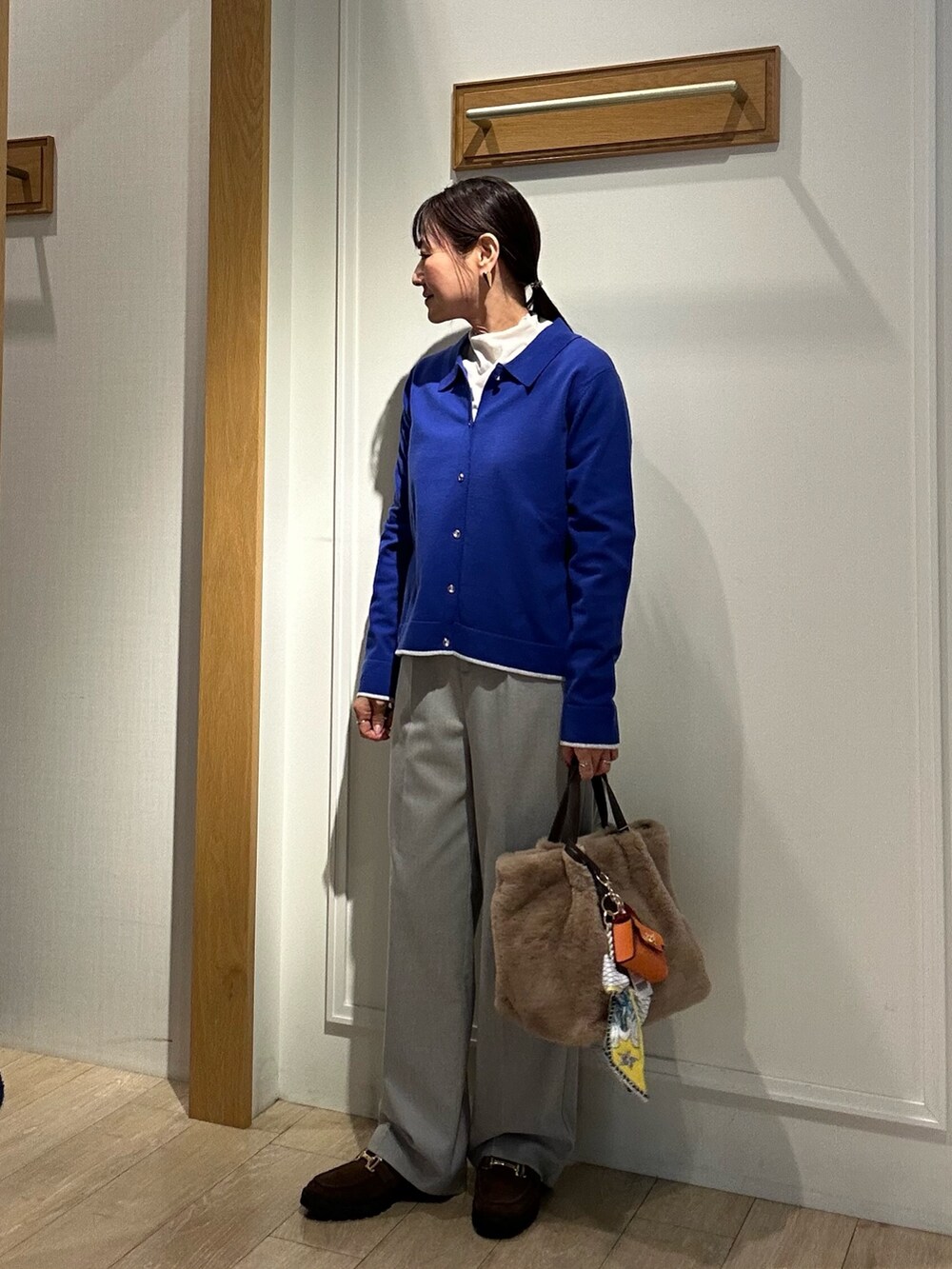 ブラウン系のローファー、ブラック系のダウンジャケット/コート、ブルー系のカーディガン/ボレロを着用したレディースの冬コーディネートの5枚目の写真