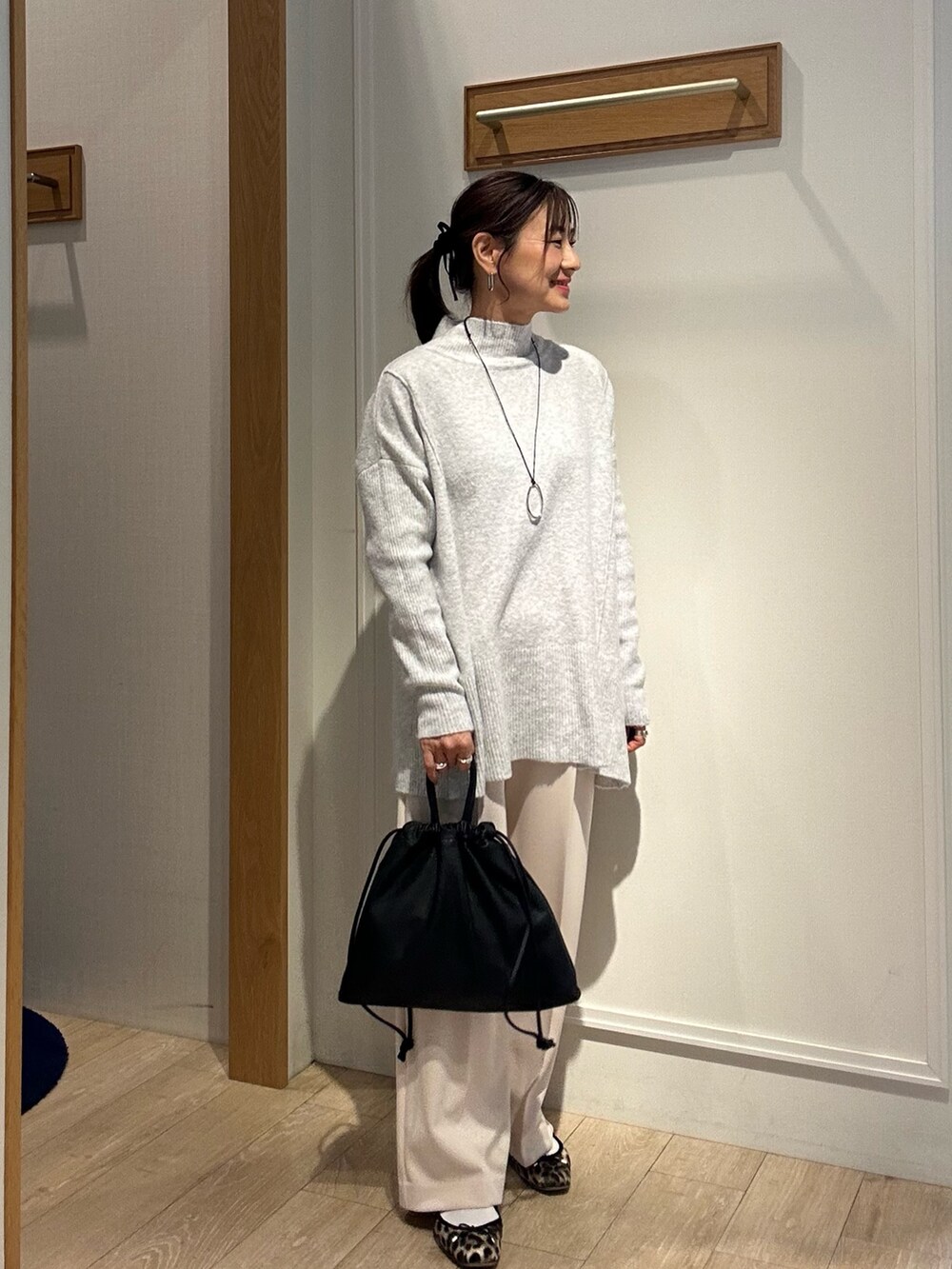 グレー系のニット/セーター、ホワイト系のその他パンツ、ブラック系のショルダーバッグを着用したレディースの冬コーディネートの2枚目の写真