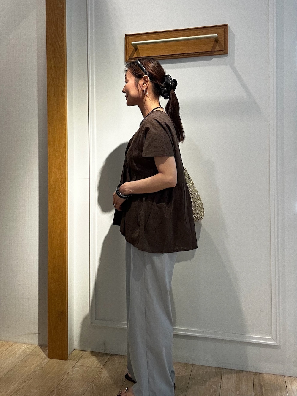 ブラウン系のシャツ/ブラウス、グレー系のその他パンツ、ゴールド系のトートバッグを着用したレディースの夏コーディネートの3枚目の写真