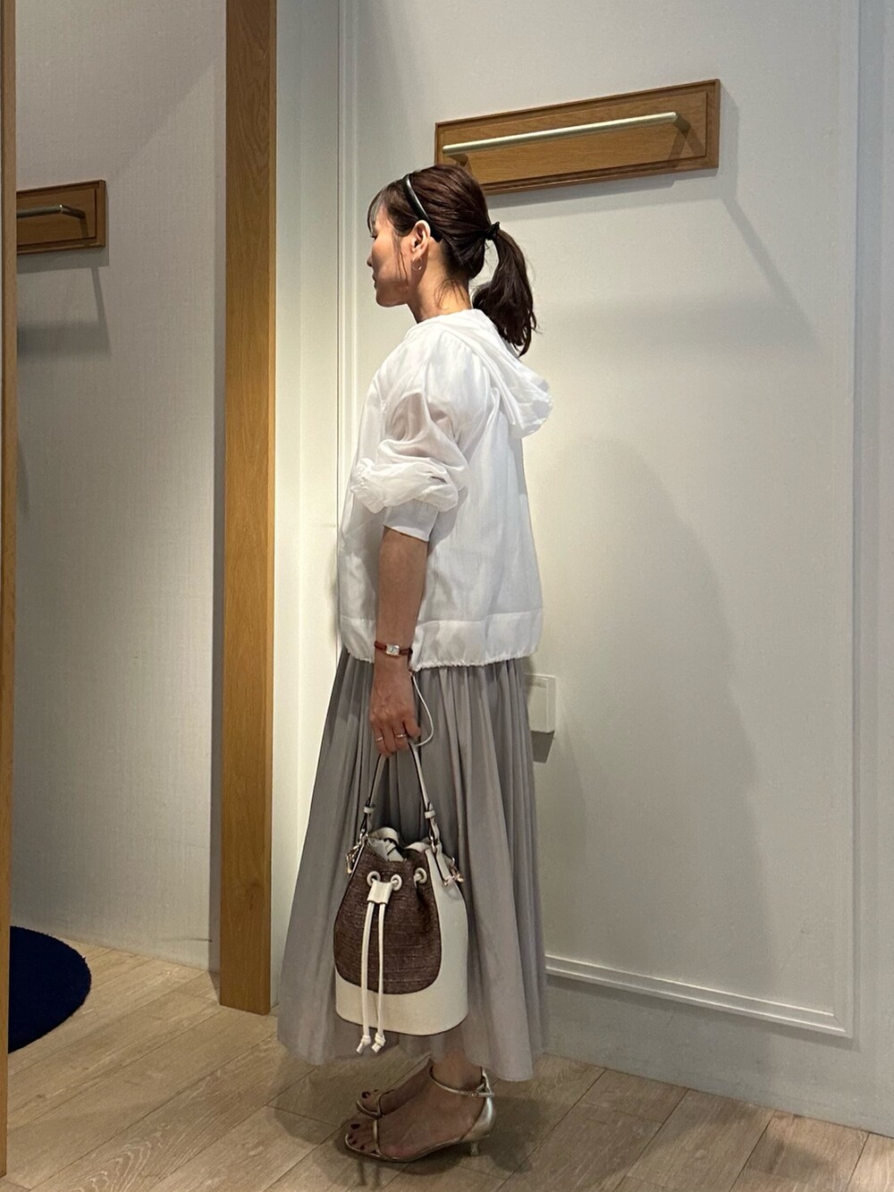 ベージュ系のスカート、ホワイト系のブルゾン、ホワイト系のTシャツ/カットソーを着用したレディースの春コーディネートの2枚目の写真