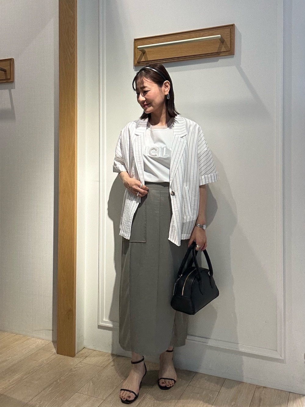 グリーン系のスカート、ホワイト系のTシャツ/カットソー、ブラック系のボストンバッグを着用したレディースの夏コーディネートの9枚目の写真