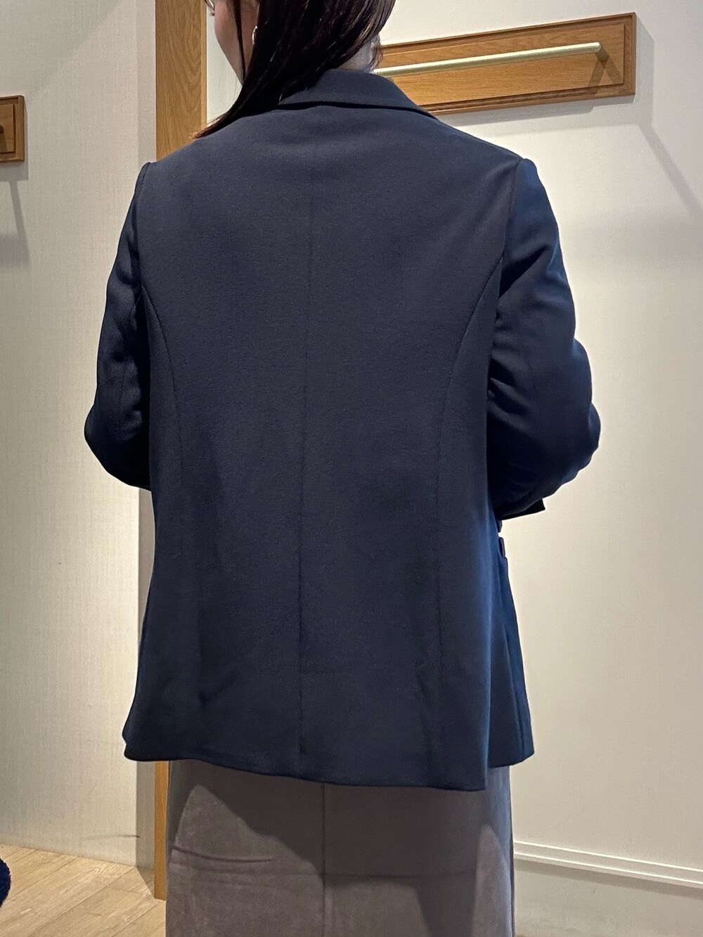 ホワイト系のニット/セーター、ブルー系のテーラードジャケット、グレー系のスカートを着用したレディースの秋コーディネートの7枚目の写真