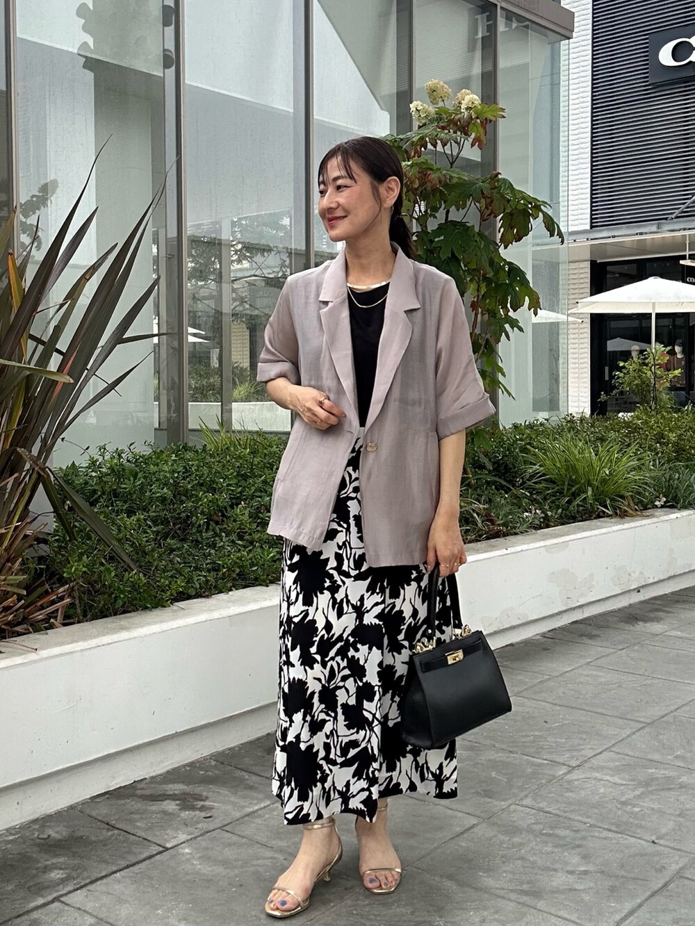 ホワイト系のワンピース、ブラック系のショルダーバッグ、ベージュ系のテーラードジャケットを着用したレディースの夏コーディネートの9枚目の写真