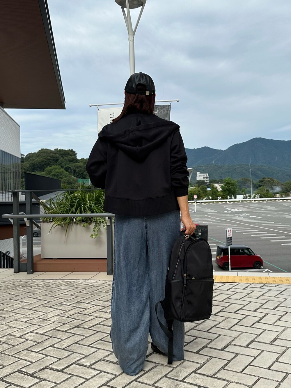 ブラック系のパーカー、ブルー系のデニムパンツ、ブラック系のバックパック/リュックを着用したレディースの秋コーディネートの4枚目の写真