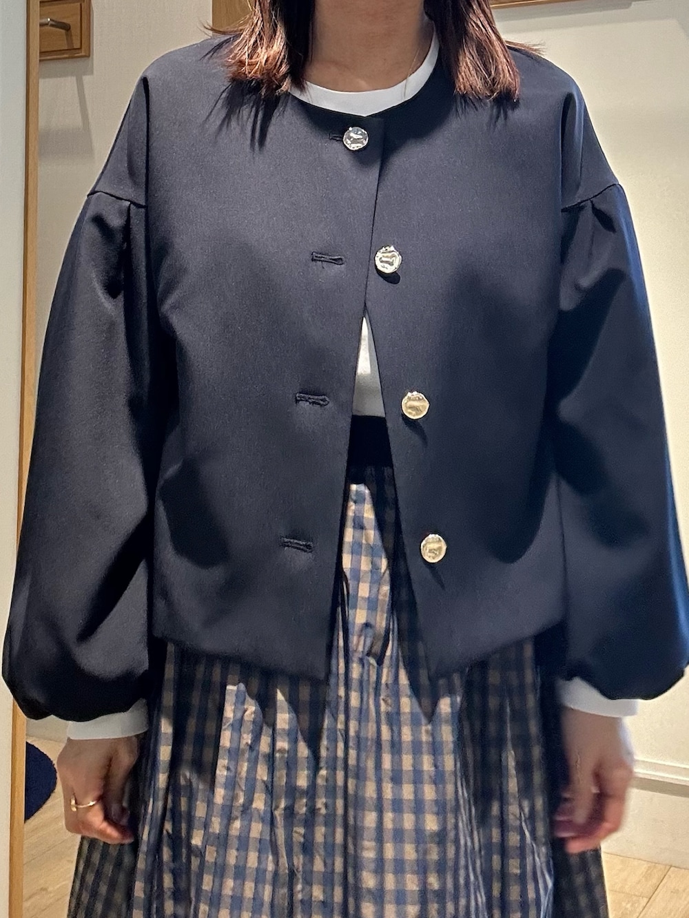 ブルー系のノーカラージャケット、ホワイト系のTシャツ/カットソー、ブラウン系のスカートを着用したレディースの冬コーディネートの5枚目の写真