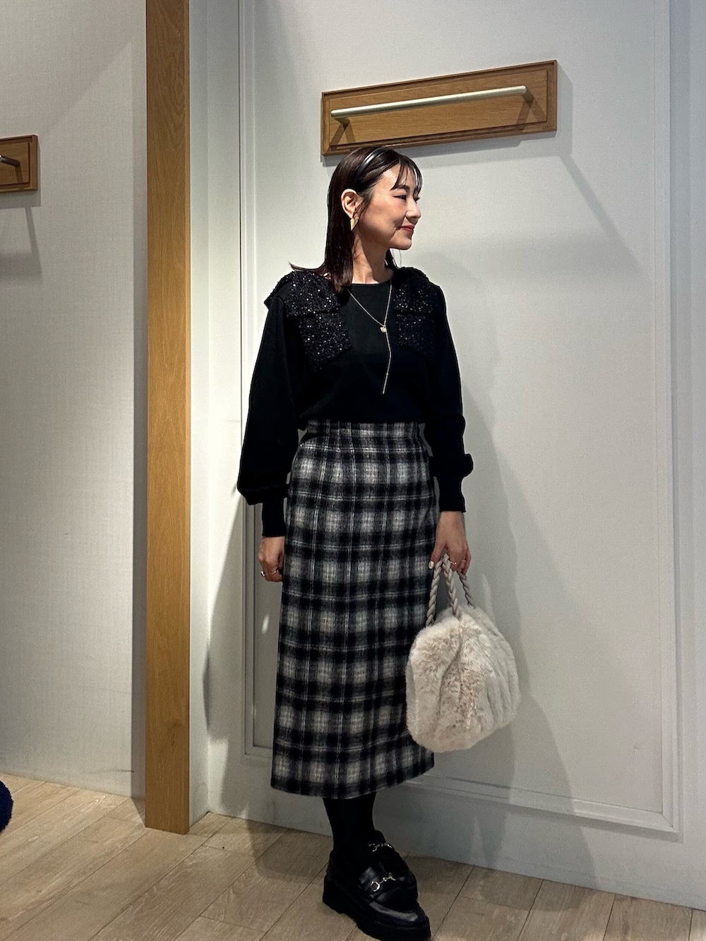 ブラック系のニット/セーター、ブルー系のスカート、ホワイト系のトートバッグを着用したレディースの冬コーディネートの4枚目の写真