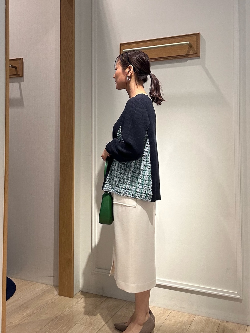 ブルー系のニット/セーター、ブルー系のスカート、グリーン系のショルダーバッグを着用したレディースの冬コーディネートの2枚目の写真