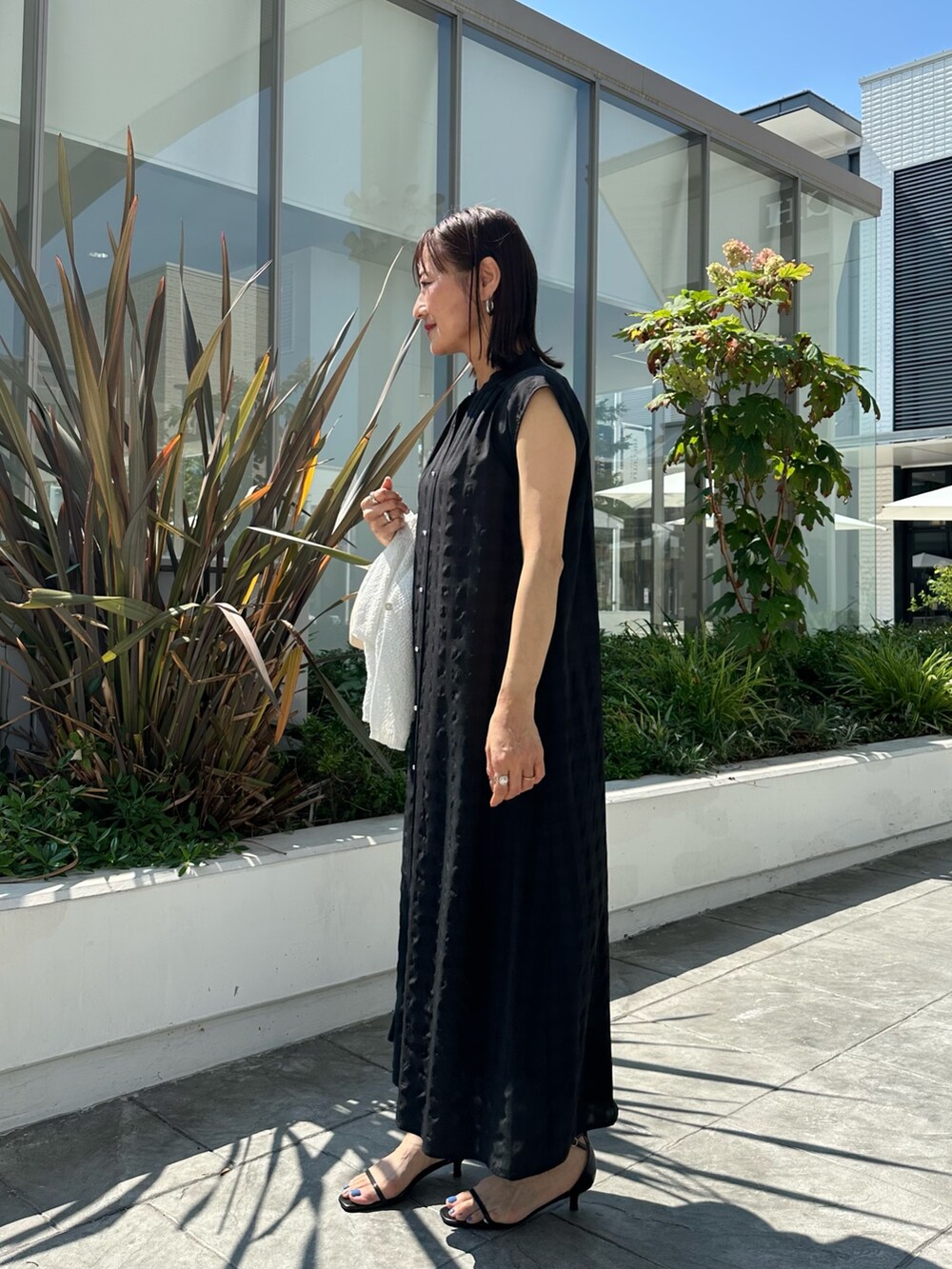 ブラック系のワンピース、ホワイト系のカーディガン/ボレロ、ブラック系のバックパック/リュックを着用したレディースの夏コーディネートの8枚目の写真