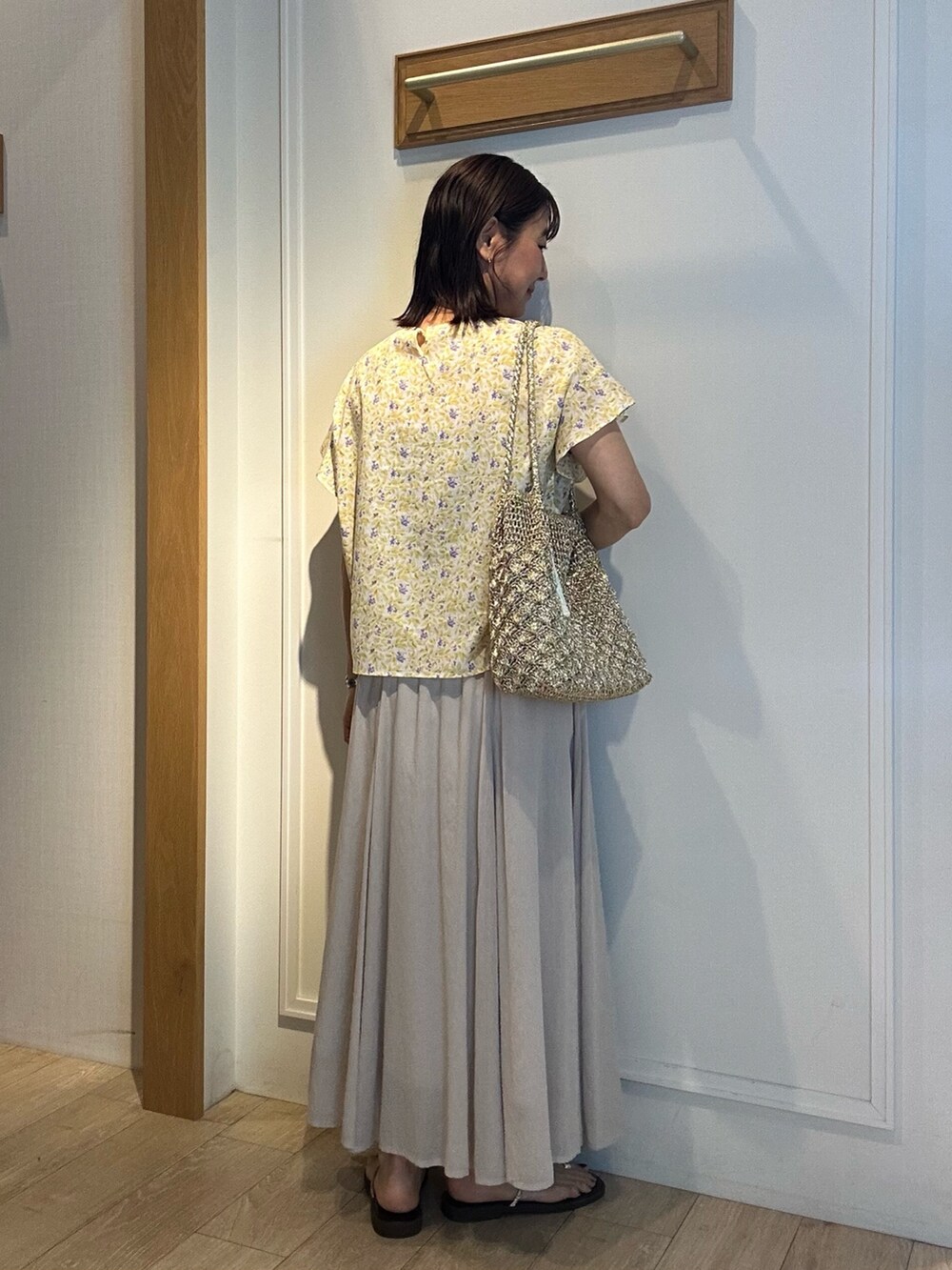 ホワイト系のスカート、イエロー系のシャツ/ブラウス、ゴールド系のネックレスを着用したレディースの春コーディネートの3枚目の写真