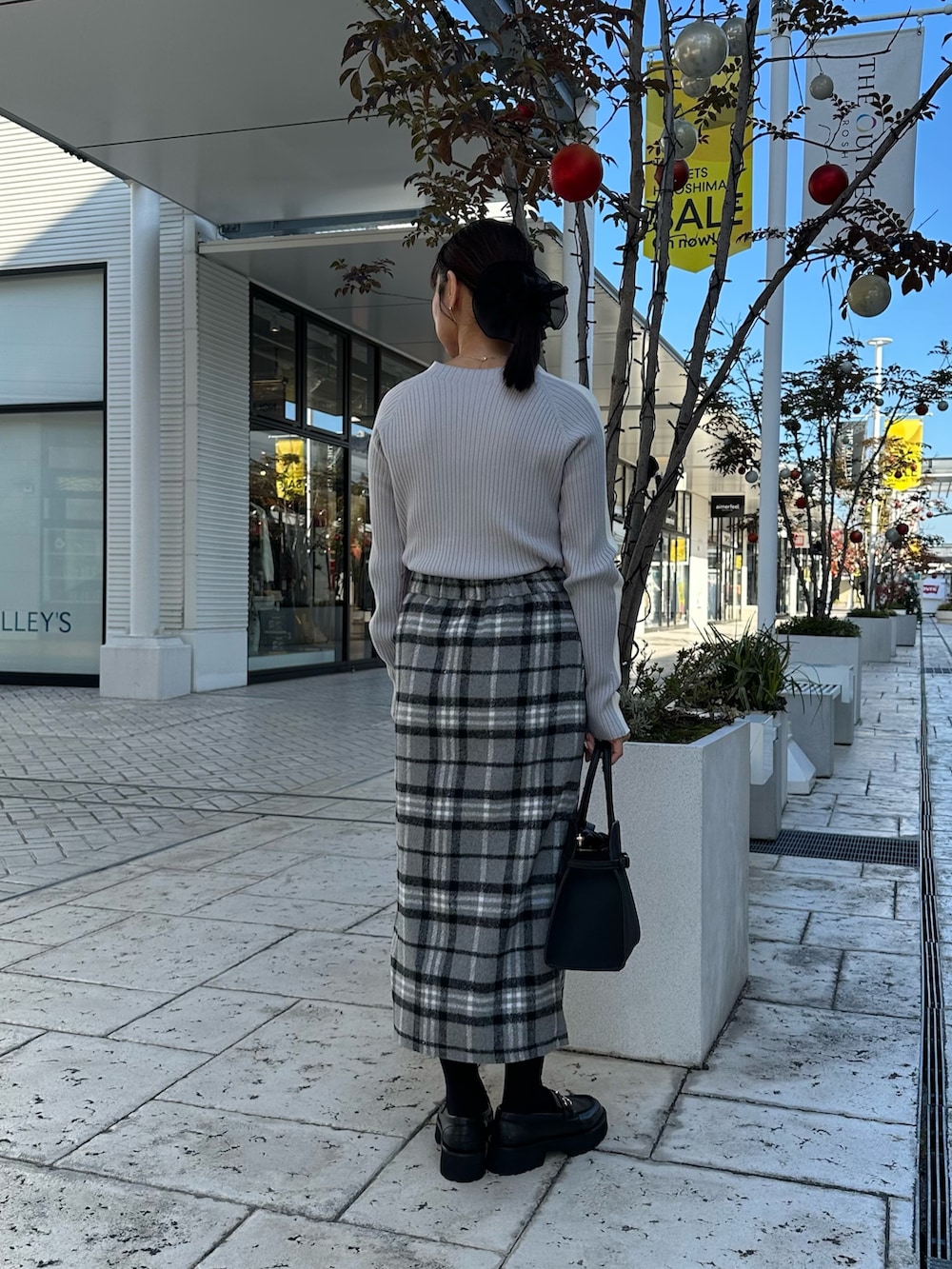 グレー系のスカート、ブラック系のトートバッグ、ピンク系のニット/セーターを着用したレディースの秋コーディネートの4枚目の写真