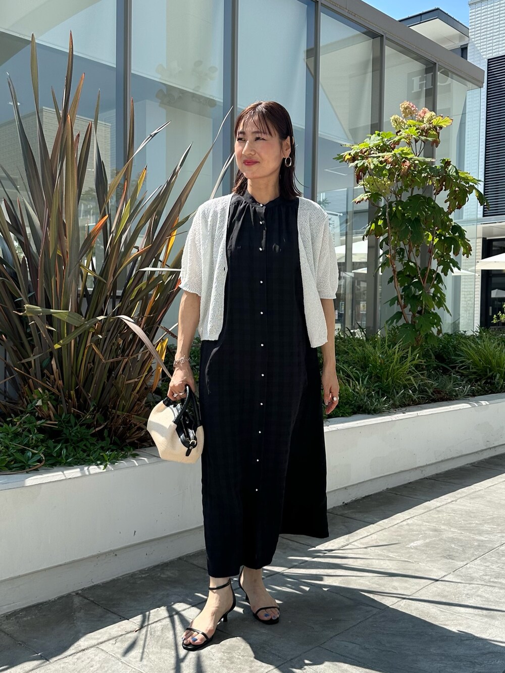 ブラック系のワンピース、ブラック系のサンダル、ホワイト系のカーディガン/ボレロを着用したレディースの夏コーディネートの7枚目の写真