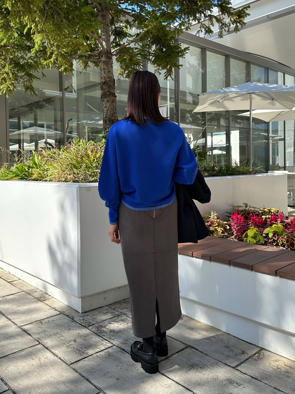 ブルー系のテーラードジャケット、ブルー系のニット/セーター、グレー系のスカートを着用したレディースの秋コーディネートの8枚目の写真