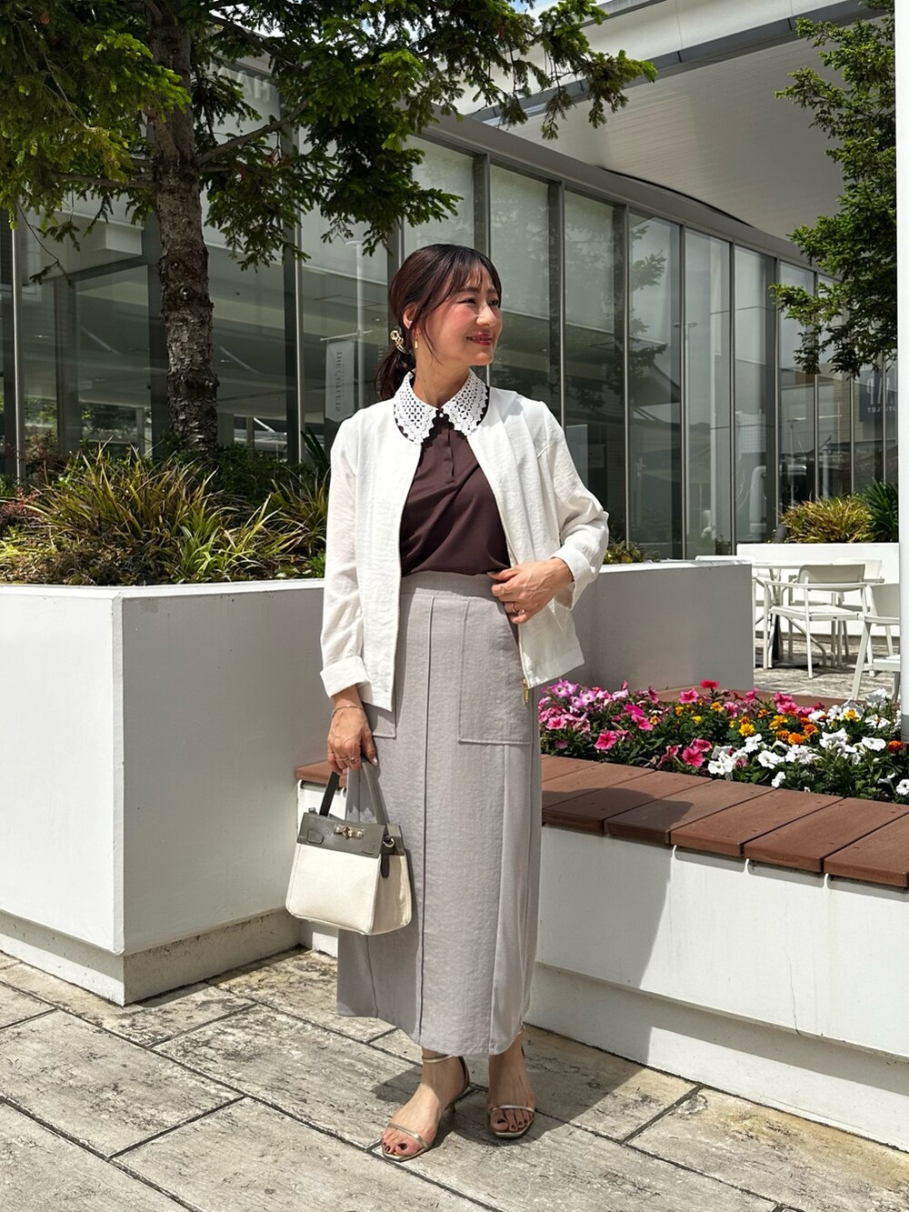 ホワイト系のノーカラージャケット、ブラック系のTシャツ/カットソー、グレー系のスカートを着用したレディースの夏コーディネートの8枚目の写真