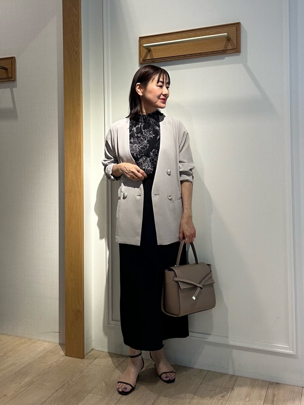 ブラック系のシャツ/ブラウス、ブラック系のスカート、ベージュ系のノーカラージャケットを着用したレディースの夏コーディネートの10枚目の写真