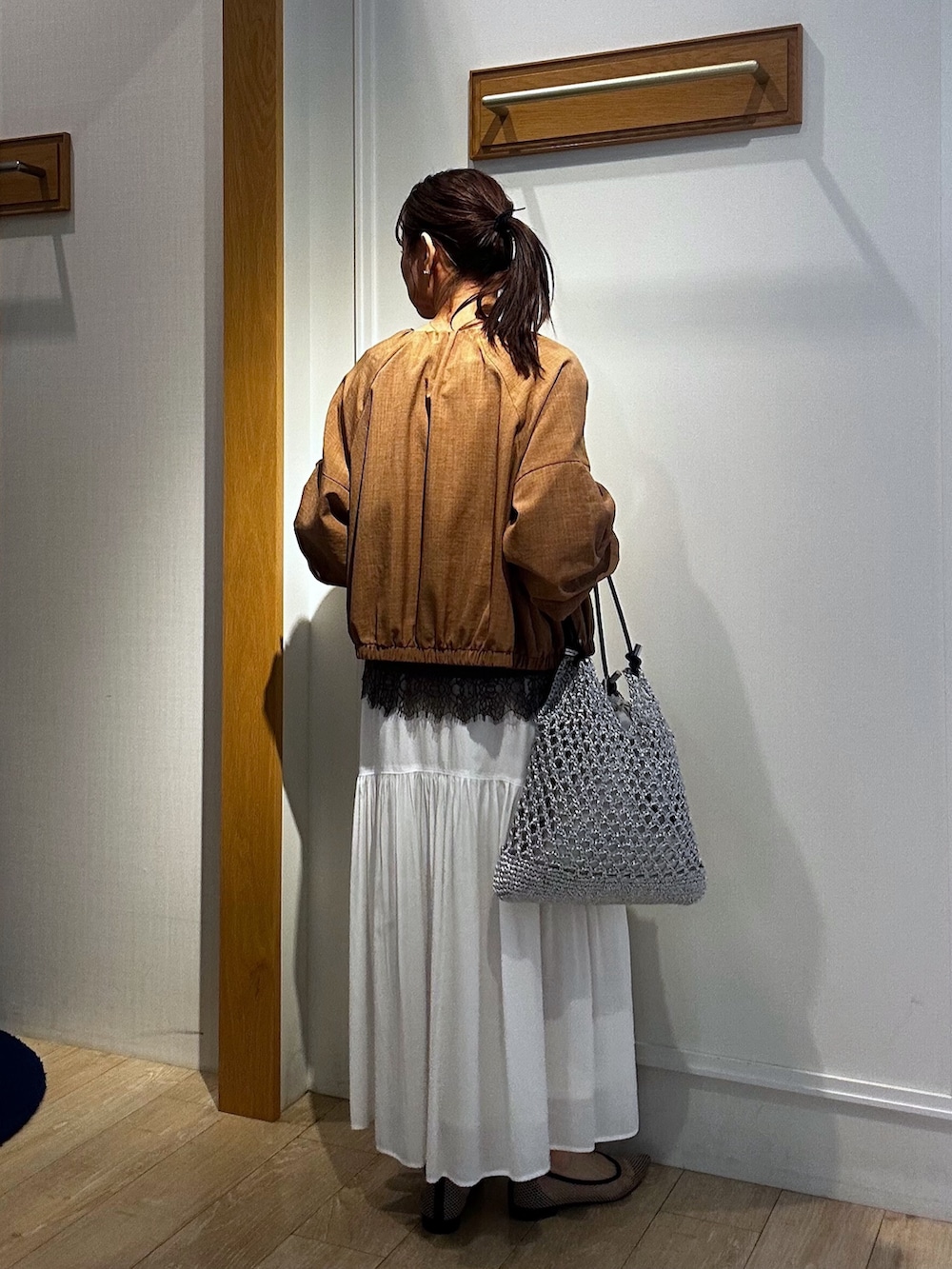 イエロー系のブルゾン、ブラウン系のTシャツ/カットソー、ホワイト系のスカートを着用したレディースの春コーディネートの3枚目の写真