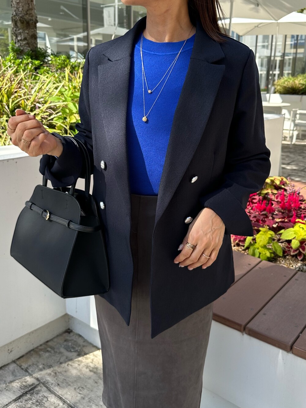 ブルー系のテーラードジャケット、ブルー系のニット/セーター、グレー系のスカートを着用したレディースの秋コーディネートの3枚目の写真