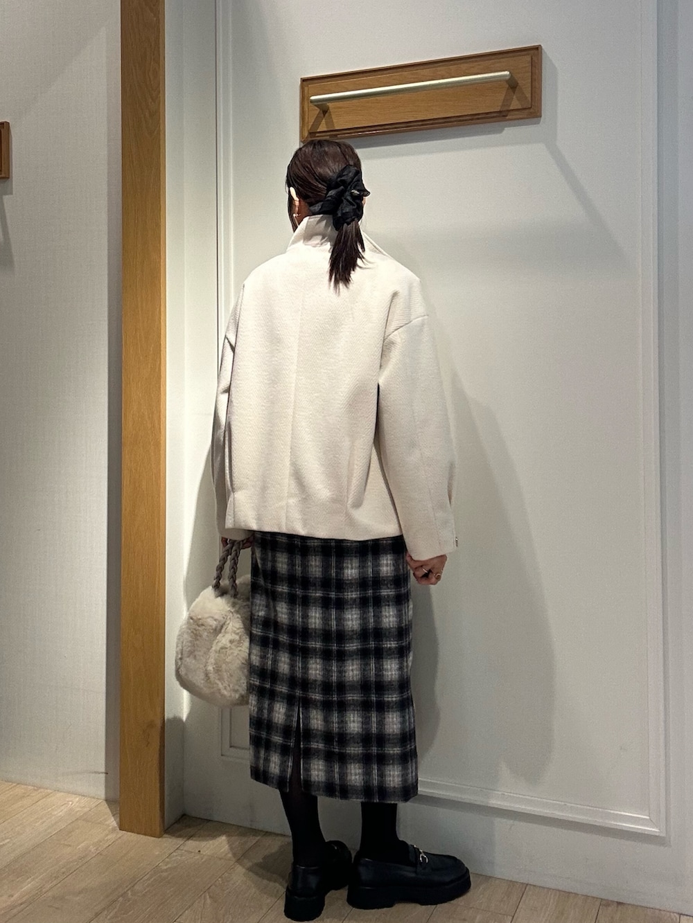 ホワイト系のトートバッグ、ホワイト系のテーラードジャケット、ブラック系のニット/セーターを着用したレディースの冬コーディネートの3枚目の写真